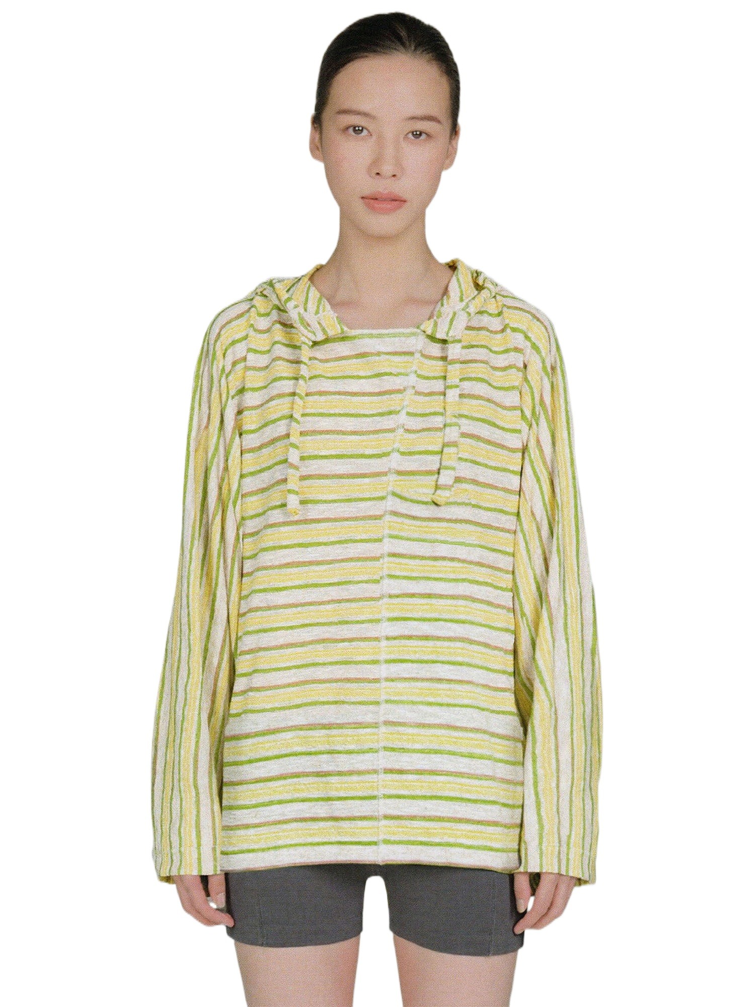 照片中,一个人正面镜头,身穿EastLyst Baja款式针织套头衫(绿黄条纹,长袖,带帽),下身穿着灰色短裤。背景为纯白色。