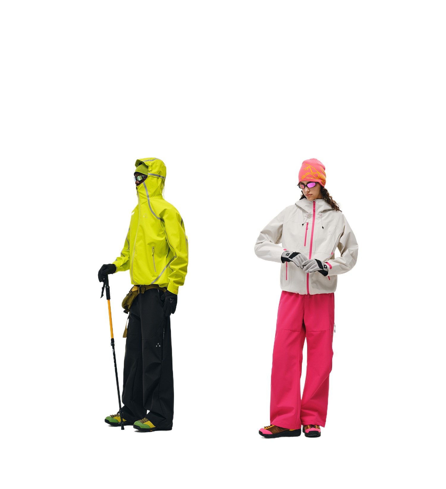 Two people wear EastLyst Softshell Joggers and colorful winter gear made from waterproof polyester; one in a yellow jacket and dark pants with a walking pole, the other in a pink hat, white jacket, and pink pants, standing against a white background.