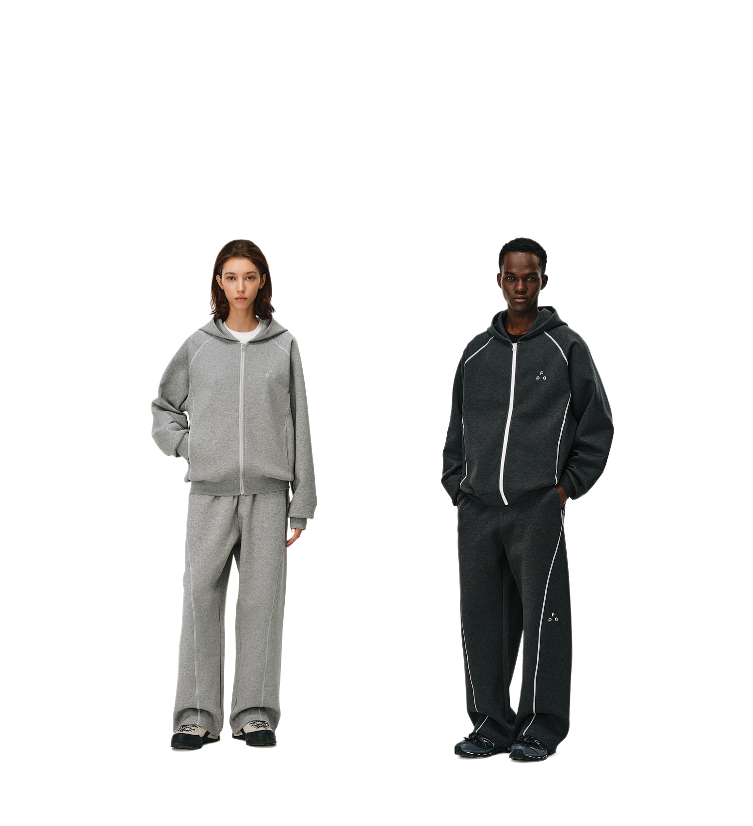 Two people wear matching relaxed-fit zip-up hoodies and EastLyst CloudWeave Draped Trousers—one pair in light gray, the other in dark gray—showcasing ultimate comfort and style against a plain white background.