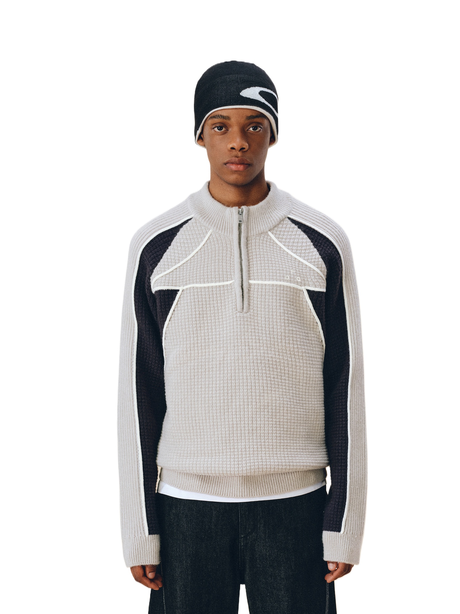 A person in the EastLyst Color Block Half Zip Sweater, featuring gray and black tones, pairs it with a black and white beanie and dark pants, standing facing forward against a plain white background.