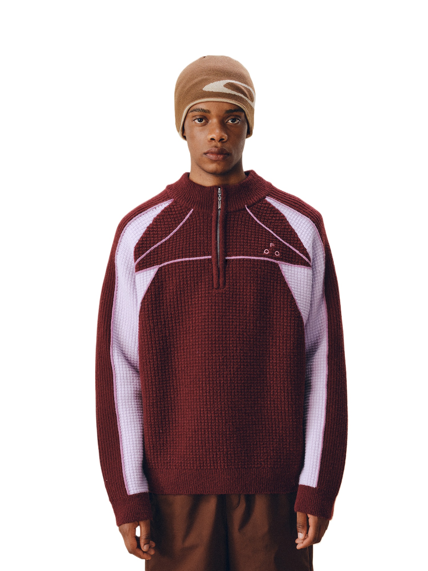 A person wears the EastLyst Color Block Half Zip Sweater, featuring maroon wool with light purple geometric patterns, paired with a brown and beige beanie and brown pants, standing against a white background.